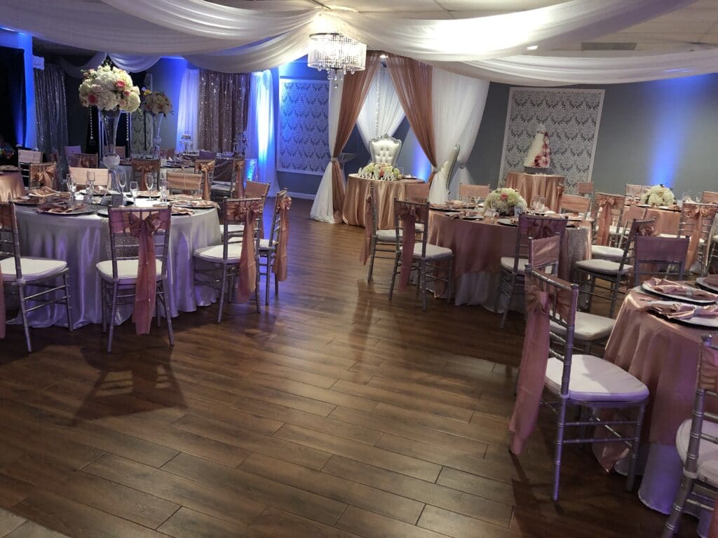 indoor wedding reception with round tables and chairs on brown wood floor